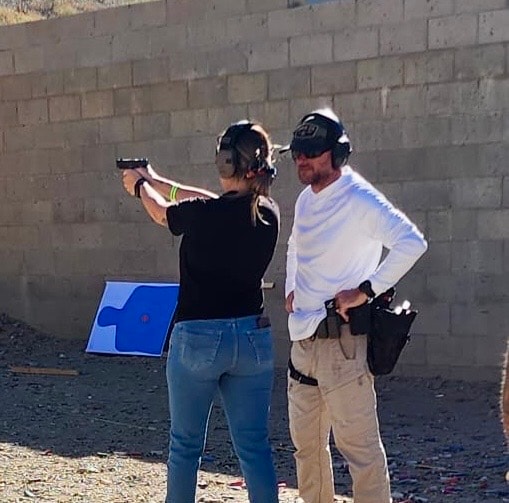 A man instructs another person on shooting at an outdoor firing range.